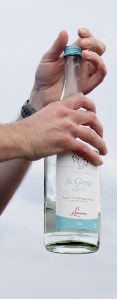 Mann öffnet eine Flasche St. Georgsquelle still