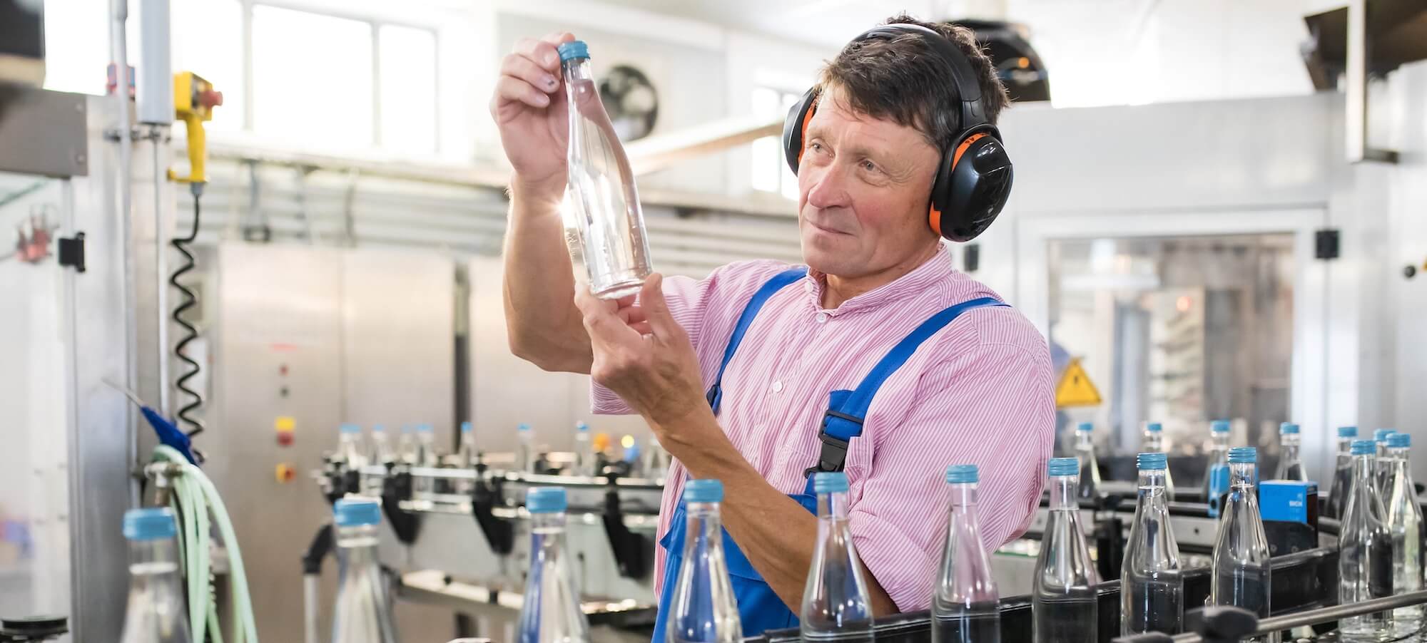 Mitarbeiter kontrolliert die abgefüllte Flasche der St. Georgsquelle still in 0,33 Liter.