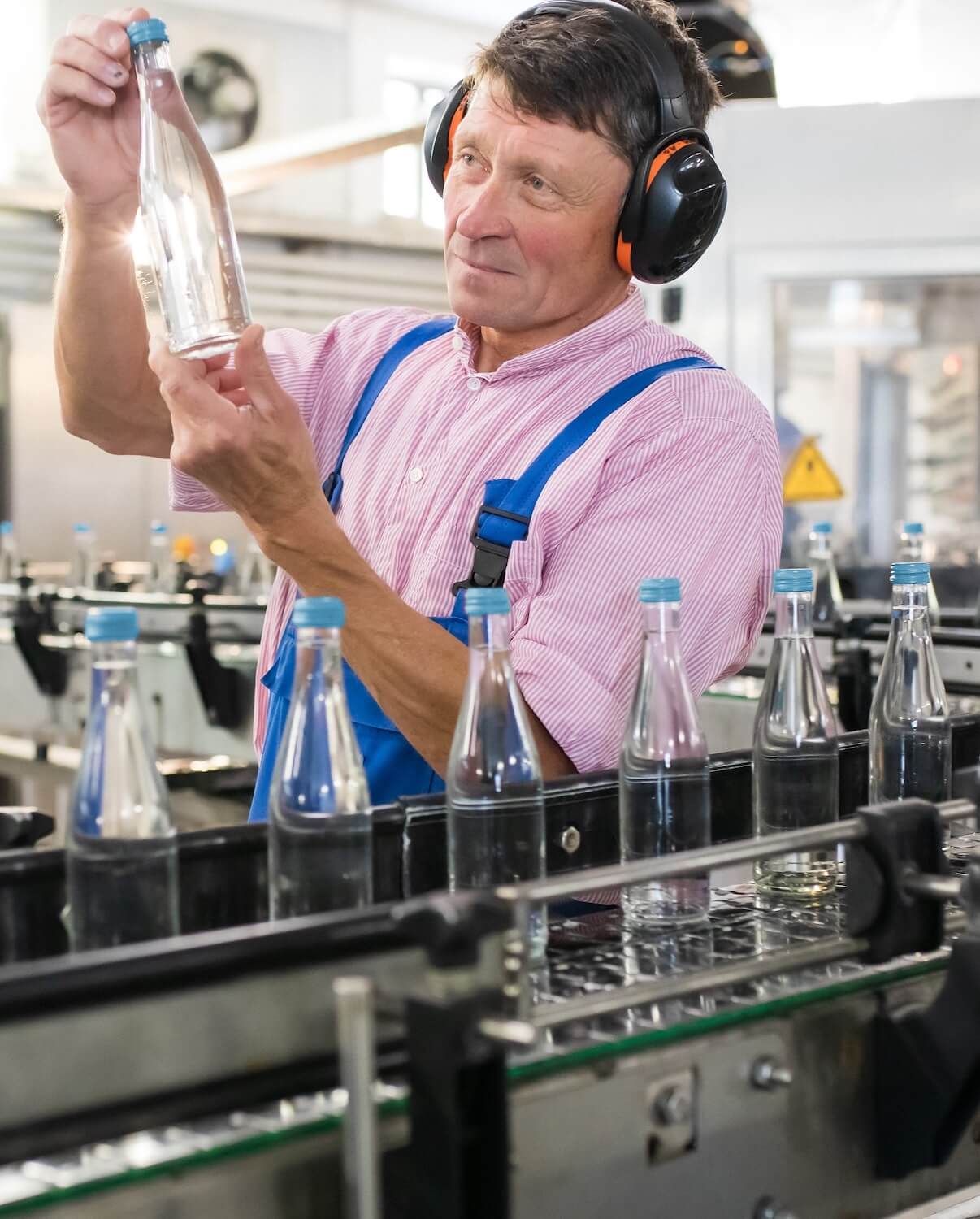 Mitarbeiter kontrolliert die abgefüllte Flasche der St. Georgsquelle still in 0,33 Liter.