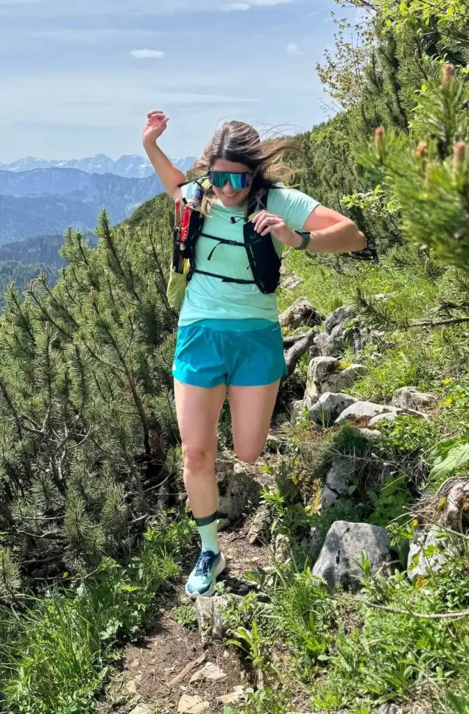 Trailrunnerin läuft lächelnd über Felsen