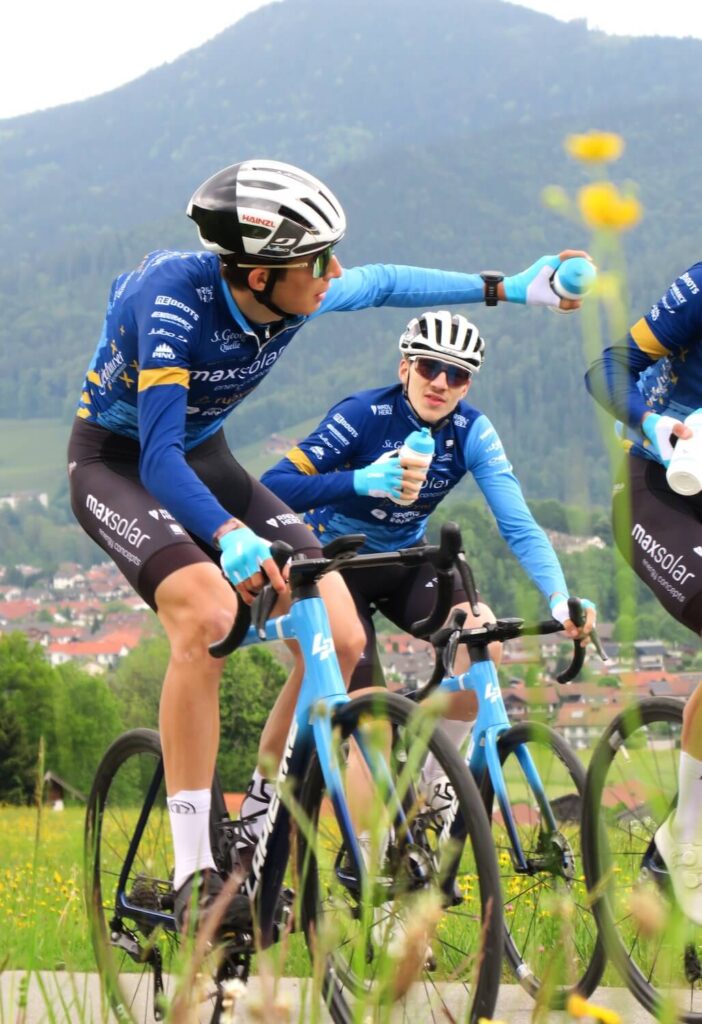 Professionelles Radfahrteam trinkt während der Fahrt Wasser aus Flaschen